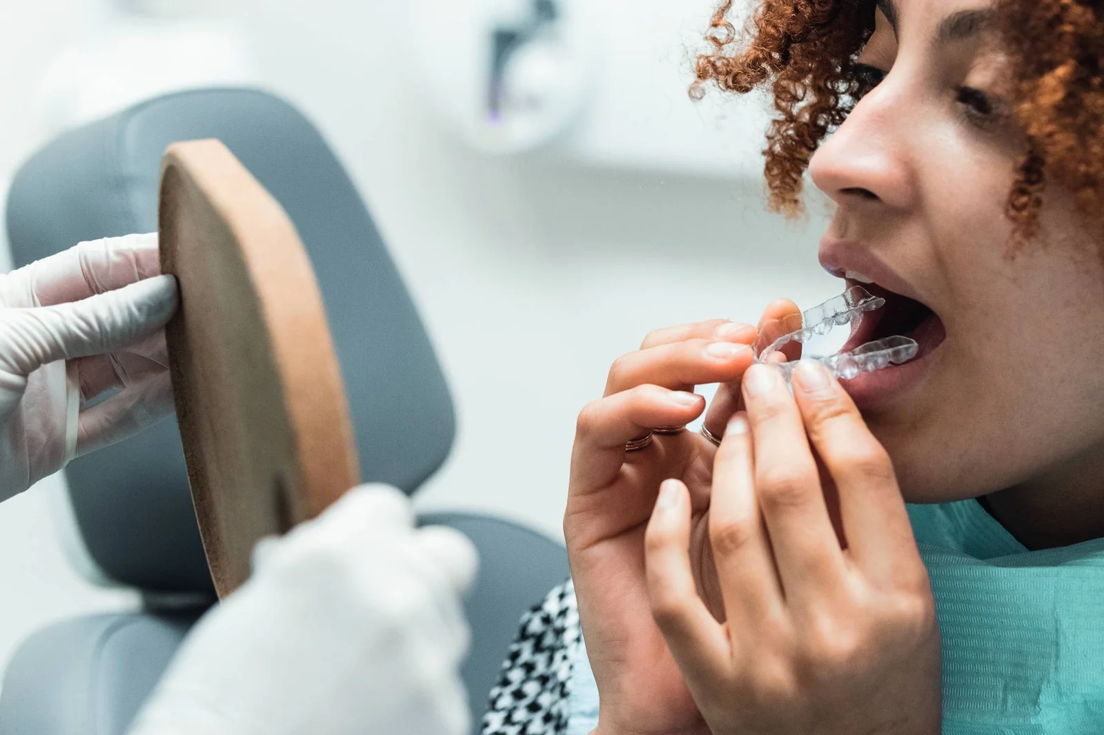 Paciente colocando alinhador transparente nos dentes em frente ao espelho na clínica Oral Mac em Jundiaí, ilustrando o que são alinhadores.