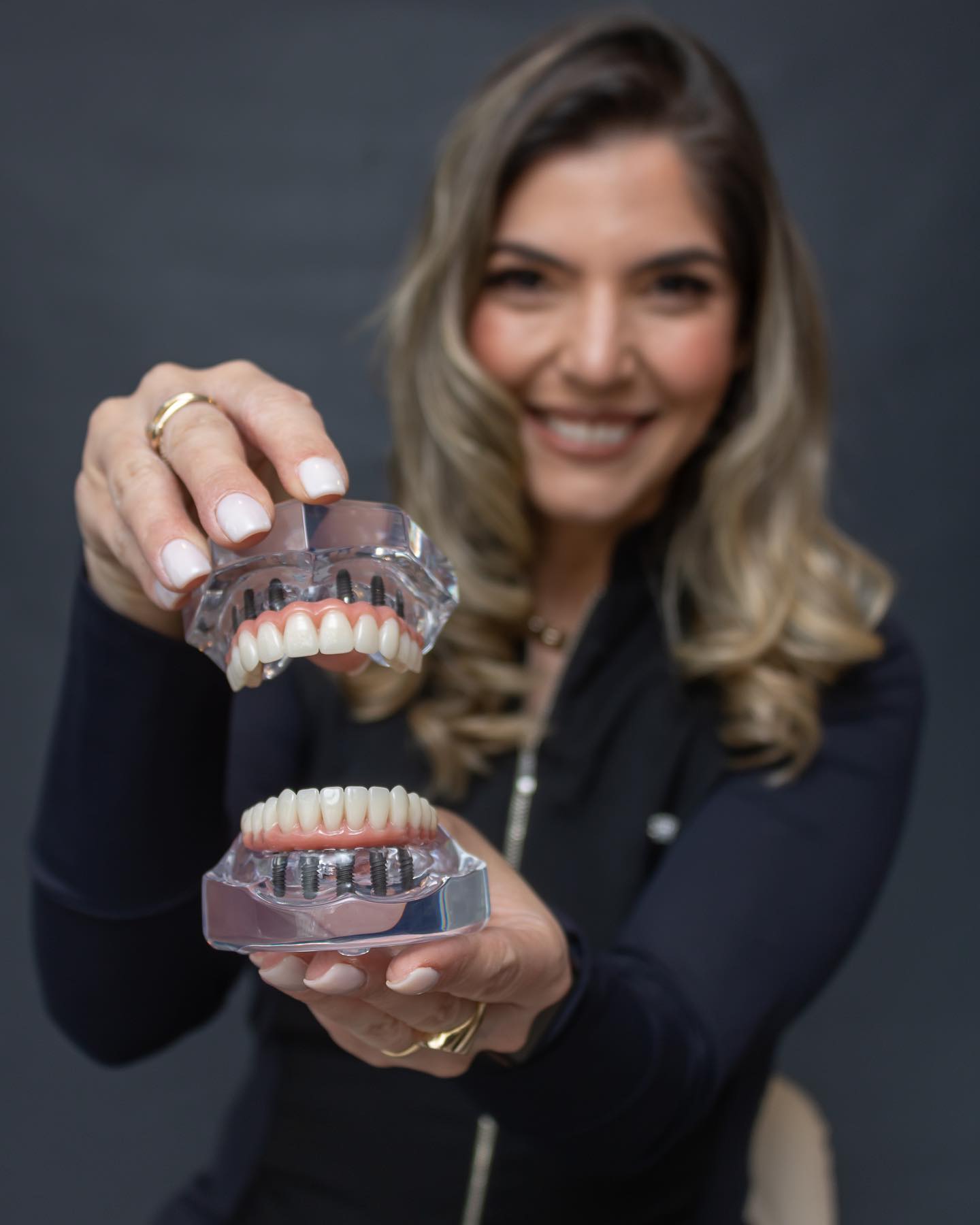 Dra. Ana Paula da Oral Mac segurando modelo de prótese protocolo fixa sobre implantes, demonstrando a solução de prótese dentária total em Jundiaí.